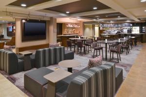 a restaurant with tables and chairs and a flat screen tv at Courtyard by Marriott Charlotte Matthews in Matthews