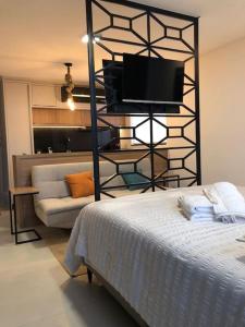 1 dormitorio con 1 cama, TV y sofá en Lindo Flat Central - Home Business en Pomerode