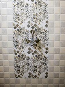 a bathroom with a tile wall with a faucet at snooze inn jodhpur in Jodhpur