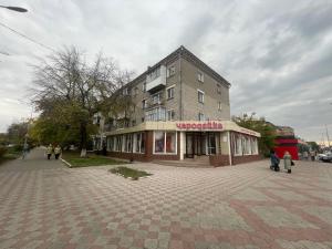 a building on a street with people walking in front of it at Квартира бизнес-класса с белым постельным кафе Маринад (Назарбаева/Интернaциональная) in Petropavlovsk