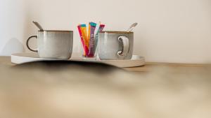 twee koffiemokken op een bord op een tafel bij Aux Fleurs de Darcy Confort Centre Ville in Dijon