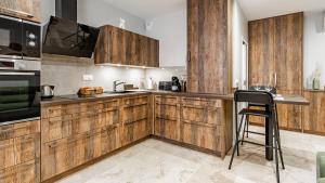 een keuken met houten kasten en een bar met een kruk bij Aux Fleurs de Darcy Confort Centre Ville in Dijon