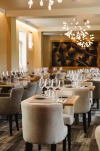 une salle à manger avec des tables, des chaises et des verres à vin dans l'établissement Le Castel Cabourg hôtel & SPA- Restaurant La Calypso, à Cabourg