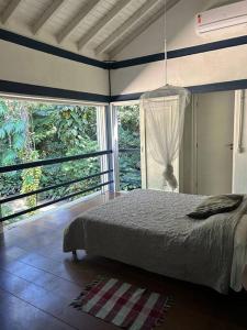 1 dormitorio con 1 cama en una habitación con ventanas en Schönes Haus direkt am Fluß in der Mata Atlantica, en São Sebastião