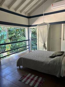 a bedroom with a bed in a room with windows at Schönes Haus direkt am Fluß in der Mata Atlantica in São Sebastião