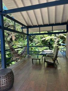 a porch with a hammock and chairs and a table at Schönes Haus direkt am Fluß in der Mata Atlantica in São Sebastião