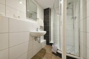 Un baño blanco con lavabo y ducha. en Ford Apartment Bremen City Center, en Bremen