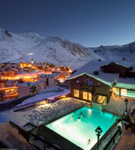 a resort with a pool in the snow at night at Hôtel Village Montana by Les Etincelles in Tignes