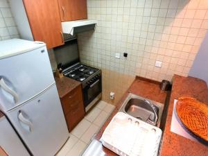 a kitchen with a sink and a refrigerator at StoneTree - Prime Location - Furnished Studio - Near Metro in Dubai