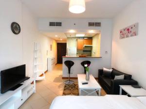 a living room with a couch and a tv and a kitchen at StoneTree - Prime Location - Furnished Studio - Near Metro in Dubai