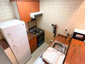a kitchen with a sink and a white refrigerator at StoneTree - Prime Location - Furnished Studio - Near Metro in Dubai
