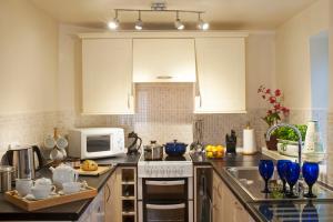 a kitchen with white cabinets and a white microwave at Stone Lodge at Combermere Abbey in Nantwich