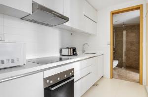 cocina blanca con fregadero y microondas en The Majestic Mile 1BR Apartment in Singapore!, en Singapur