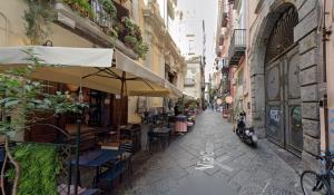 an alley with tables and chairs and an umbrella at Napuletanata in Naples