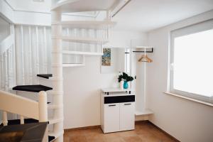 a white spiral staircase in a white room with a window at Idylische Ferienunterkunft in Heitersheim