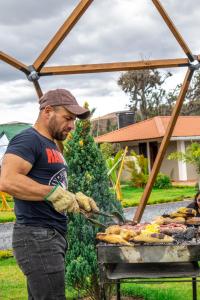 człowiek używający młynka do gotowania jedzenia na grillu w obiekcie Magia Verde Glamping w mieście Tinjacá
