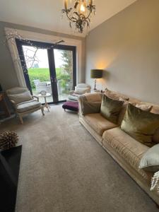 a living room with a couch and a chandelier at Woodend Cottage in Dumfries