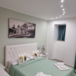 Dormitorio blanco con cama con manta verde y almohadas en Al Punto Giusto en Catania