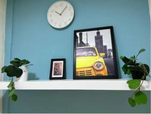 a clock on a shelf with a picture of a yellow car at Small Private Partition Room in Al Barsha 1 Near Metro in Dubai