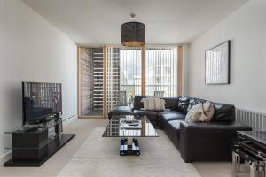 sala de estar con sofá negro y TV en City Stay Apartments - Vizion, en Milton Keynes