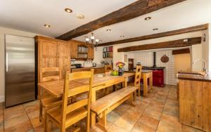 a kitchen with wooden cabinets and a wooden table and benches at Country House with Heated Swimming Pool & Gardens in Rhiw