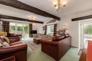a living room with leather furniture and a fireplace at Country House with Heated Swimming Pool & Gardens in Rhiw