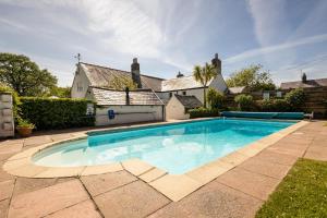 a swimming pool in front of a house at Country House with Heated Swimming Pool & Gardens in Rhiw
