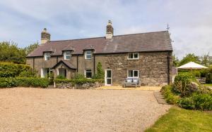a large stone house with a gravel driveway at Country House with Heated Swimming Pool & Gardens in Rhiw