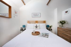 Un dormitorio con una cama blanca con una cesta. en Laity Vean Farmhouse and Hideaway, en Carbis Bay