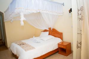 um quarto com uma cama com uma cortina branca e uma cama sidx sidx em Bekam Hotel em Keruguya