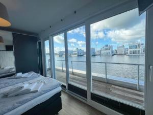 a bedroom with a large window with a view of the water at Schwimmendes Haus am Pier in Olpenitz