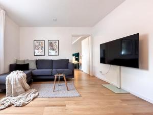 een woonkamer met een blauwe bank en een flatscreen-tv bij Appartio: Geräumige, moderne Ferienwohnung für Gruppen/Familien in Stuttgart