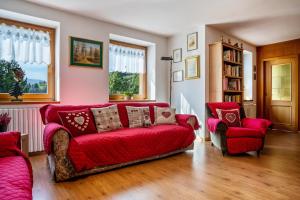 a living room with a red couch and two chairs at Casa Magda in Tesero