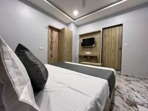 een slaapkamer met een groot bed en een televisie bij HOTEL KRISHNA in Ahmedabad