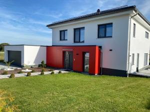 a white house with red doors and a yard at Beautiful Apartment with a huge private terrace 