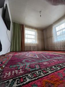 une chambre vide avec un tapis au sol dans l'établissement Ata konush, à Sufi-Kurgan