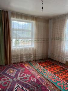 Cette chambre dispose d'un grand tapis en face d'une fenêtre. dans l'établissement Ata konush, à Sufi-Kurgan