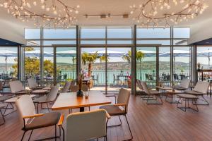 um restaurante com mesas e cadeiras e janelas grandes em Sedartis Swiss Quality Hotel em Thalwil