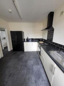 uma cozinha com um frigorífico preto e armários brancos em The Dublin Packet Apartment em Holyhead