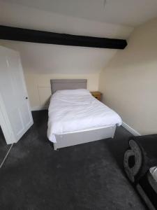 a small bedroom with a white bed and a chair at The Dublin Packet Apartment in Holyhead