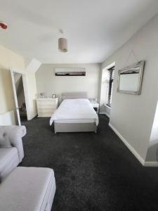 a white bedroom with a bed and a couch at The Dublin Packet Apartment in Holyhead