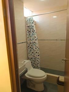 y baño con aseo y cortina de ducha. en Confortable habitación doble frente al Aeropuerto, en Lima