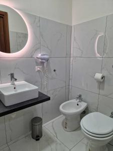 La salle de bains blanche est pourvue d'un lavabo et de toilettes. dans l'établissement B&B Pompeii Living Dream, à Pompéi