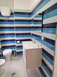 La salle de bains est pourvue de murs rayés bleus et blancs et de toilettes. dans l'établissement B&B Pompeii Living Dream, à Pompéi
