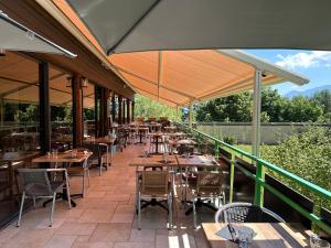un restaurante al aire libre con mesas, sillas y sombrillas en Logis Le Chalet, en Saint-Maurice-en-Trièves