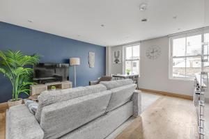 a living room with a gray couch and a blue wall at Contemporary 2 BR apt, town centre by tent serviced apartments in Chertsey