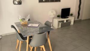 a dining room table with chairs and a television at Maison tendance avec jardin, centre village, Alpilles, familles in Eyragues