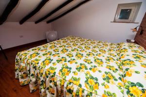 ein Bett mit einer Blumendecke in einem Schlafzimmer in der Unterkunft Casa Vacanze Etna in Piedimonte Etneo