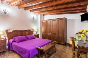 een slaapkamer met een paars bed en een tafel bij Casa costera playa de Tasarte in San Nicolás