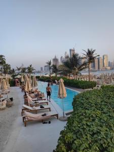 una persona che cammina accanto a una piscina con ombrelloni di 7 Palm Jumeirah a Dubai